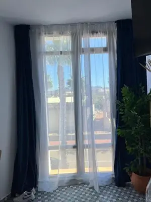a window with blue curtains and a potted plant at ALZIRA BONITA APARTAMENTO CON DOS HABITACIONES CON VISTAS AL RiO JUCAR in Alzira