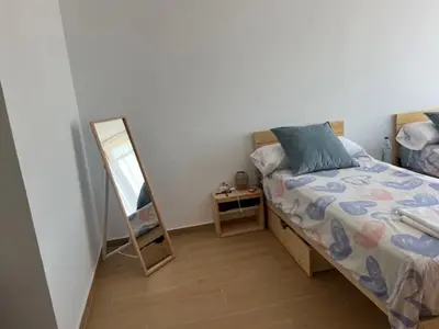 a bedroom with a bed next to a mirror at ALZIRA BONITA APARTAMENTO CON DOS HABITACIONES CON VISTAS AL RiO JUCAR in Alzira