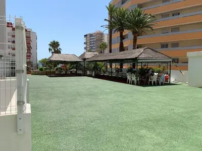 a gazebo with tables and chairs on a lawn at Estupendo apartamento con piscina y vistas al mar in Cullera