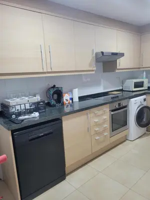 a kitchen with wooden cabinets and a black dishwasher at APARTAMENTO MODERNO y ACOGEDOR in Canet de Berenguer