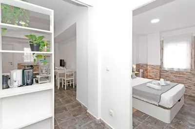 a white bedroom with a bed and a kitchen at GuestReady - Apartamento en Benicalap in Valencia