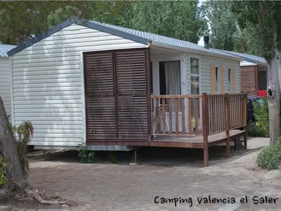 a large wooden cabin with a porch and a deck at Camping Valencia el Saler in El Saler