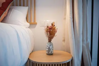 a vase with flowers on a table next to a bed at Lofts plaza JM Orense B in Valencia