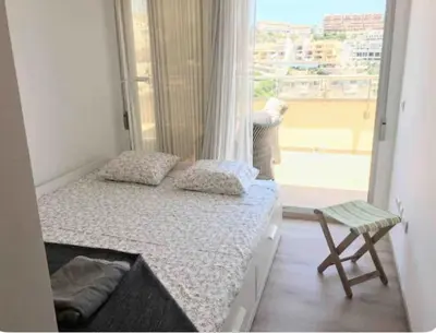 a small bedroom with a bed and a window at Espectacular apartamento en Cullera con vistas al mar in Faro de Cullera