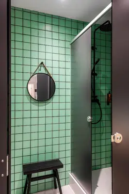 a green tiled bathroom with a mirror and a stool at Colo Colo Hostel Valencia - Single Private Beds in Valencia