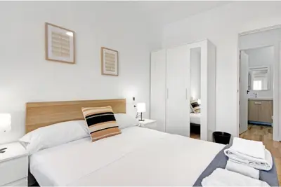 a white bedroom with a large white bed and a bathroom at Apartamento 4 habitaciones y 2 baños in Puerto de Sagunto