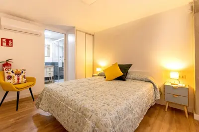 a bedroom with a bed and a yellow chair at Apartamento Beniloft - Housevanlive in Valencia