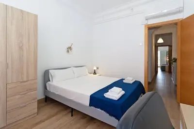 a white bedroom with a bed and a chair at GuestReady - Valencia's Sushine Terrace in Valencia