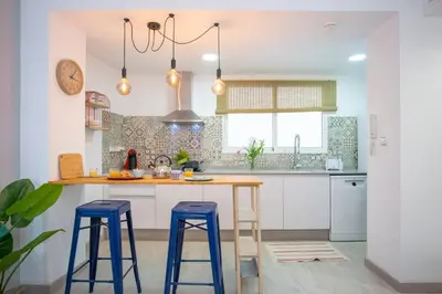 a kitchen with white cabinets and blue stools at GuestReady - A joyful stay in Poblats Marítims in Valencia