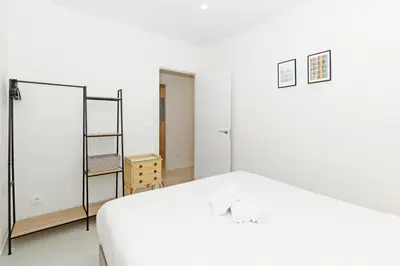 a white bedroom with a bed and a shelf at GuestReady - Piso moderno con vistas a la Marina in Valencia