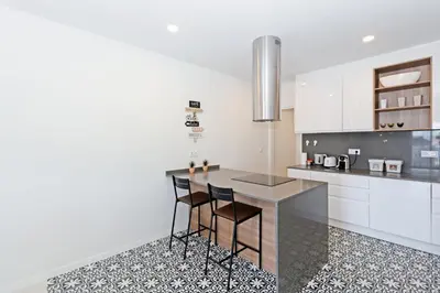 a kitchen with white cabinets and a counter with stools at GuestReady - Piso moderno con vistas a la Marina in Valencia