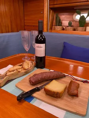 a bottle of wine and a plate of meat and cheese at Velero en puerto de valencia in Pinedo