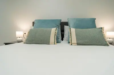 a white bed with blue pillows at VLC HOST- Sant Jordi in Valencia