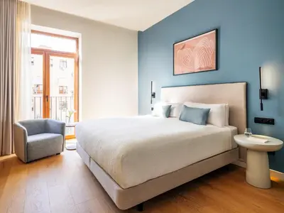 a bedroom with a large bed and a chair at Numa Valencia La Xerea in Valencia