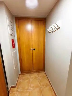 a hallway with a wooden door in a room at Apto en Cullera con terraza, piscina, parking y wifi gratis in Cullera