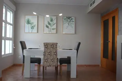 a dining room with a white table and chairs at Apto en Cullera con terraza, piscina, parking y wifi gratis in Cullera