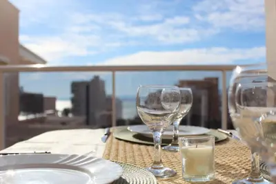 two wine glasses sitting on a table with a view at Apto en Cullera con terraza, piscina, parking y wifi gratis in Cullera