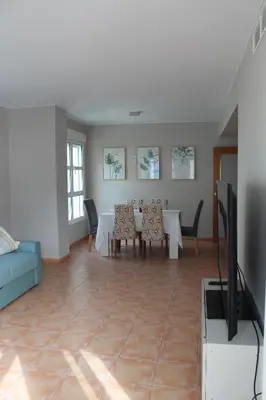 a living room with a dining table and a tv at Apto en Cullera con terraza, piscina, parking y wifi gratis in Cullera