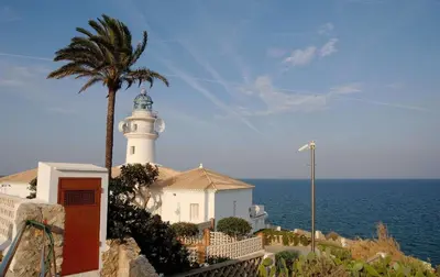 a lighthouse with a palm tree in front of the ocean at Hotel Santamarta in Cullera