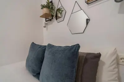 a couch with two pillows and a plant on the wall at VLC HOST - Ausias March in Valencia