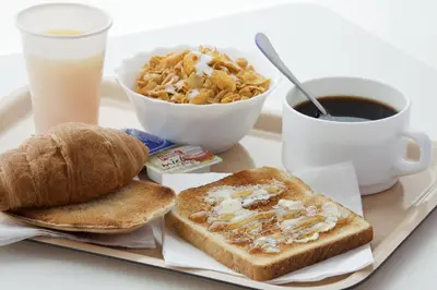 a tray with toast bread and a cup of coffee and a cup of milk at Ibis Budget Valencia Alcasser in Silla