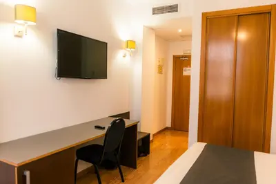 a hotel room with a desk and a television on the wall at Plaza Alaquas in Alaquas