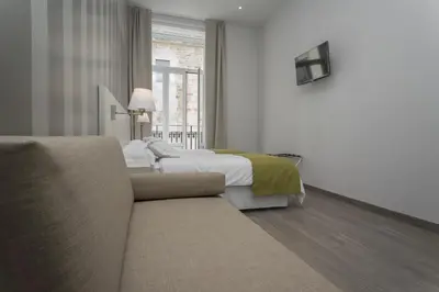 a bedroom with a bed and a couch and a window at Hotel San Lorenzo Boutique Plaza in Valencia