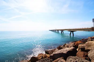 a bridge over the ocean next to the water at Vacances à la plage in Puerto de Sagunto