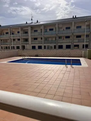 a building with a swimming pool in front of a building at 1Apartamento con piscina 2 linea de playa con acc valencia in Puzol