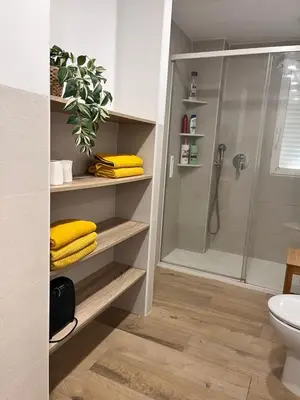 a bathroom with a shower and yellow towels at 1Apartamento con piscina 2 linea de playa con acc valencia in Puzol