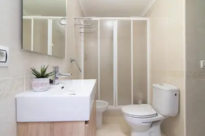 a white bathroom with a toilet and a sink at Global Vacacional, Apartamento en Puerto de Sagunto in Puerto de Sagunto
