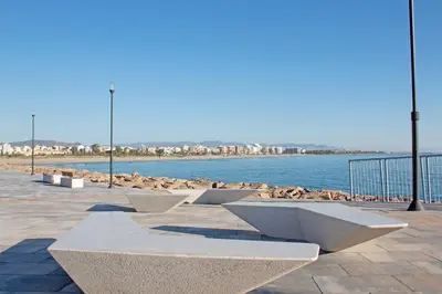 a row of benches next to a body of water at Global Vacacional, Apartamento en Puerto de Sagunto in Puerto de Sagunto