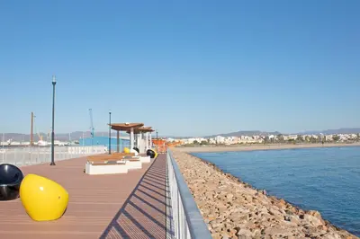 a wooden boardwalk next to a body of water at Global Vacacional, Apartamento en Puerto de Sagunto in Puerto de Sagunto