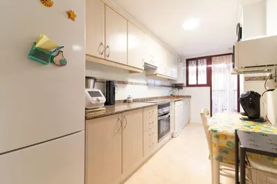 a kitchen with white cabinets and a table at Global Vacacional, Apartamento muy cerca de la playa de Puerto de Sagunto in Puerto de Sagunto