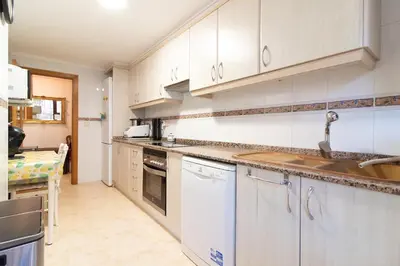 a kitchen with white cabinets and a sink at Global Vacacional, Apartamento muy cerca de la playa de Puerto de Sagunto in Puerto de Sagunto