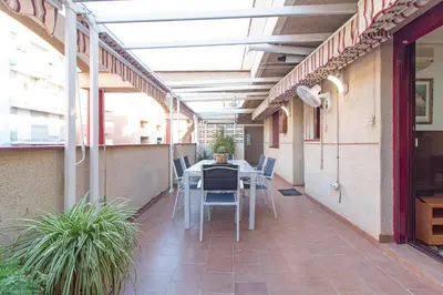 an outdoor patio with a table and chairs in a building at Global Vacacional, Apartamento muy cerca de la playa de Puerto de Sagunto in Puerto de Sagunto