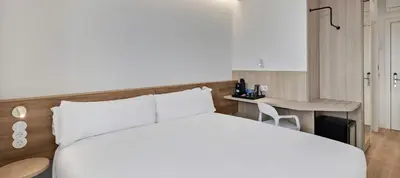 a bedroom with a white bed and a desk at B&B HOTEL Valencia Alcàsser in Alcácer
