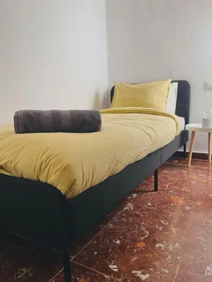 a bed with yellow pillows on it in a room at Habitación Cardenal 1 in Valencia