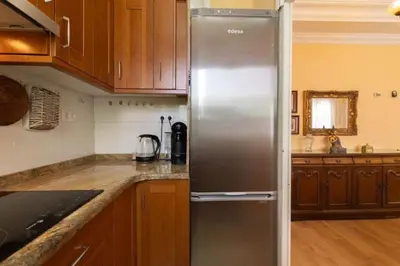 a stainless steel refrigerator in a kitchen with wooden cabinets at Central Apartment Sleeps 6 Fast Wi-Fi 2 Bathrooms in Valencia