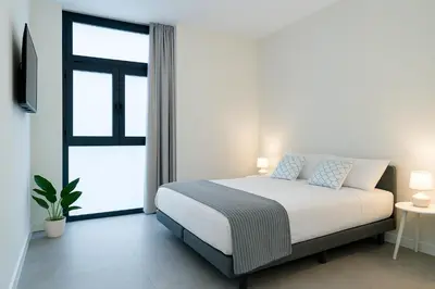 a white bedroom with a bed and a window at Formidable Apartments in Valencia