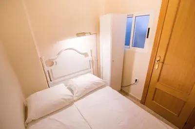 a small room with a white bed with a door at Valencia central apartment in Valencia