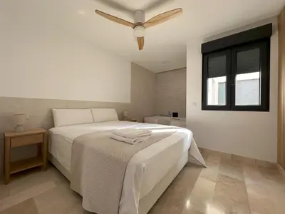 a bedroom with a white bed with a ceiling fan at Bellver Home Apartamentos in Chella