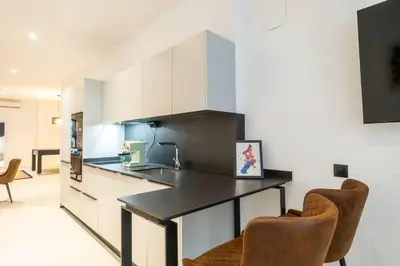 a kitchen with a black counter and two chairs at Flats nou Mestalla in Valencia