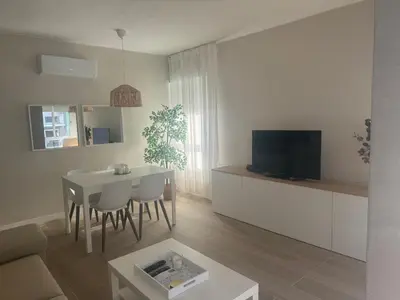 a white living room with a table and a television at Ca Maruja in Cullera