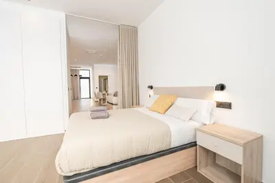 a bedroom with a white bed and a mirror at Suite Deluxe Valencia - Ciudad de las Artes in Valencia