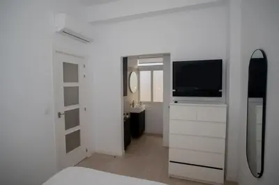a white room with a television and a bathroom at Apartamento acogedor frente a Torres de Serrano in Valencia