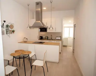 a kitchen with a table and two chairs and a counter at Apartamento acogedor frente a Torres de Serrano in Valencia