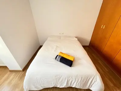 a small bedroom with a white bed with a yellow towel on it at Cute and Cosy Room in Valencia