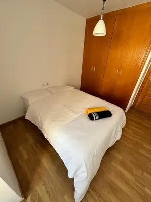a white bed with a brown towel on top of it at Cute and Cosy Room in Valencia