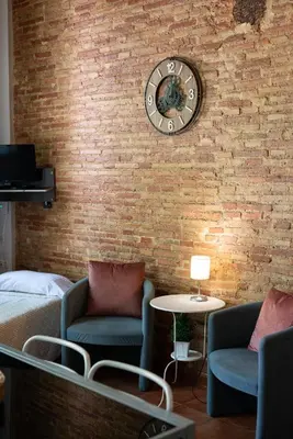 a room with a brick wall with a clock and chairs at Apartamentos Mercado Central in Valencia
